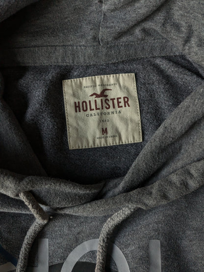 Hollister Hoodie. Donker Grijs gemêleerd met opdruk. Maat M.